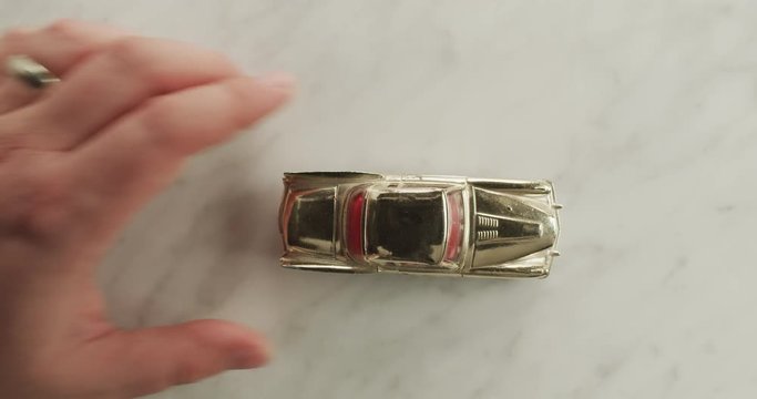 A gold toy car drives out onto a marble table in multiple angles.