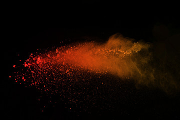 Explosion of colored powder isolated on black background. Power or clouds splatted. Freez motion of orange dust exploding. - obrazy, fototapety, plakaty