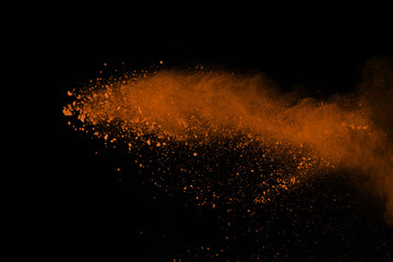 Explosion of colored powder isolated on black background. Power or clouds splatted. Freez motion of orange dust exploding.