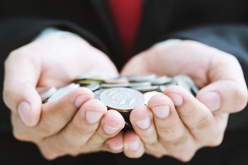close up money coins in hands Business man in suit and red necktie. business and savings financial concept.
