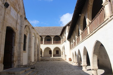 Fototapeta na wymiar Courtyard of Timios Stavros Monastery, located near the mountain village Omodos, surrounded by two-story buildings with arcades.