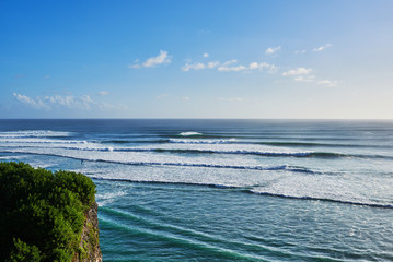 Coastline with beautiful rocky cliffs and turquoise wavy sea. Scenic coastal landscape of high cliff at sun day Bali island, Indonesia.