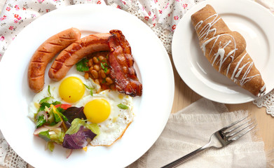 Breakfast with eggs, sausages and bacon. Light colors.