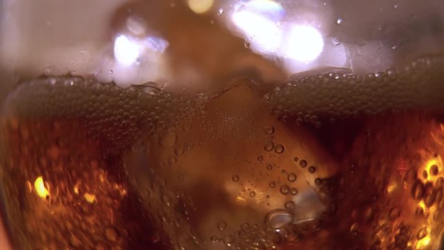 Cola pouring into the glass with Ice cubes and bubbles. Food background. Soda Close-up.