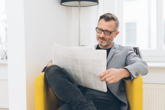 Mature man wearing glasses reading newspaper
