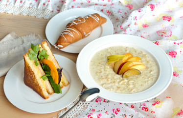 Breakfast with oatmeal, sandwich, fruit and croissant