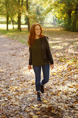 Red-haired smiling woman walking in park
