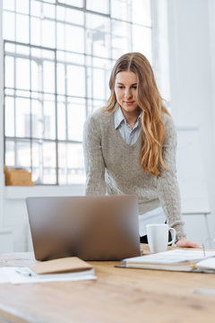 Businesswoman standing working on a laptop