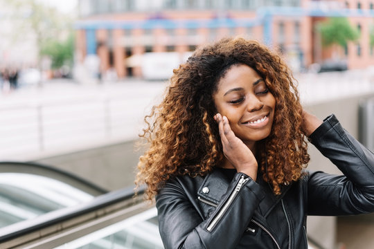 Smiling black woman listening music on earphones