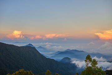 Idyllic morning scene of valley in fog, mist with mountain between land and bright sky covered in sunlight as beautiful  background.