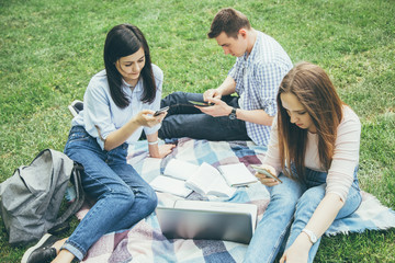 Group of college students sitting outdoors using mobile phones