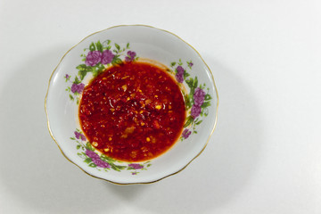 Top shot of juicy red tomato and pepper paste mix in white plate