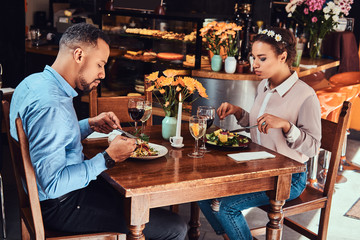 Beautiful African-American couple in love having a great time together at their dating, an attractive couple enjoying each other, eating in restaurant.