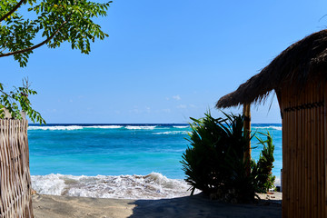 Beautiful seascape with a noisy foaming waves and beach bamboo hut view towards the turquoise ocean. Sea surf during high tide. Summer holidays. Travel concept to the sea. Summer seascape.
