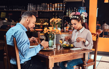 Beautiful African-American couple in love having a great time together at their dating, an attractive couple enjoying each other, eating in restaurant.