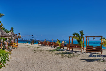 Romantic gazebo lounge at tropical resort. Empty wooden lounge beds on a beautiful beach on the background of a shining turquoise ocean. Summer morning. Relaxing private sunbed on beautiful beach.
