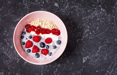 Smoothie bowl with chia seeds, muesli, jam and berries on stone background