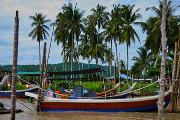 Obraz na płótnie Canvas Boats parked in fishing village. Fisherman village. Many fishing boats moored at old wooden pier. Traditional thai fisherman long tail boat in a fishermen village, Thailand, Asia.