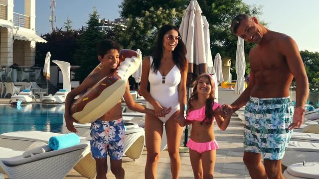 Happy pretty family having rest together near the swimming pool

