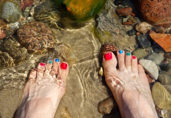 nice female feet immersed in sea water, painted nails