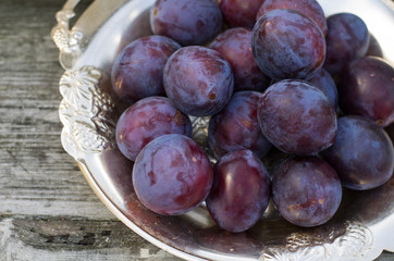 Спелые синие сливы на тарелке