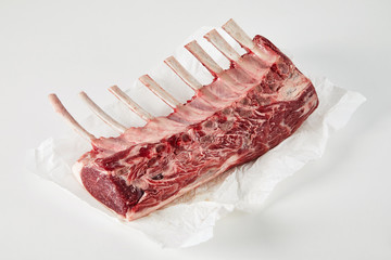 Raw lamb chop on paper against white background