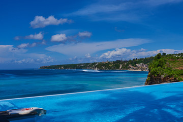 Obraz premium luxury summer vacation, travel and tourism concept. Man at the swiming pool near the sea relax moment. Silhouette of a man at the edge of infinity swimming pool, looking at the sea.