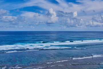 Tropical beach with rocky mountains and clear water of Indian ocean. View of turquoise bay with rocks and fluffy sky cloud. Clear water of the lagoon. Turquoise water background. Travel concept.