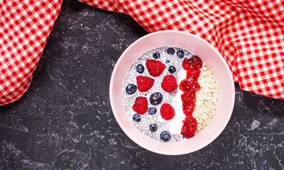 Smoothie bowl with chia seeds, muesli, jam and berries on stone background