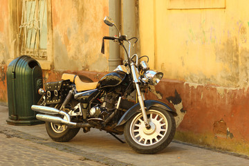 Fototapeta na wymiar Side view on a vintage motorbike parked againt grunge yellow wall