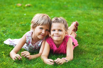 Portrait of Two Little Girlfriends / Sisters Lying Down on Grass