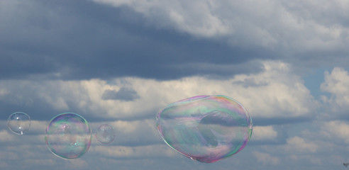 Big soap bubbles on the background of clouds and blue sky.