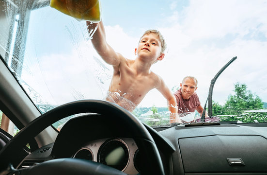 Son helps his father wash a car