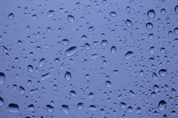 Rain drops on a windowpane in blue tone