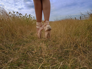 junge Ballerina steht mit Spitzenschuhen im Dünengras auf einem Wanderweg in den Dünen