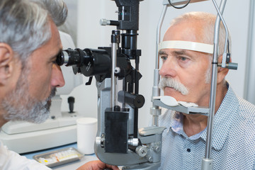 senior taking an eye test examination at opticians