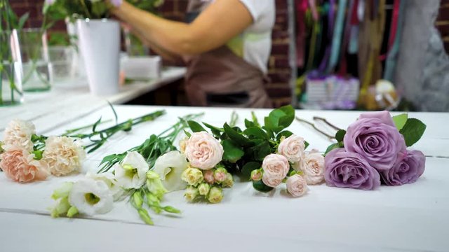 Defocused female florist putting flowers on working table preparing to floral composition arrangement. shopping, sale, floristry, small business and consumerism concept