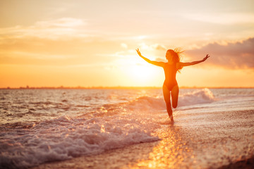 Fototapeta na wymiar carefree woman dancing in the sunset on the beach.