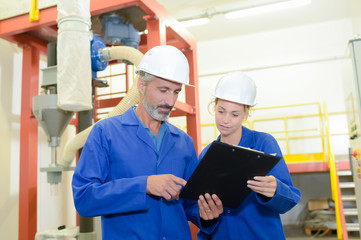 Two factory workers looking at clipboard