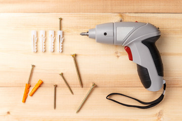 Electric screwdriver and various screws. Set of hand tools on wooden table. Instruments on wooden background. Repair tools. Top view. Flat lay. Close-up. Copy space