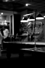 finished cocktail glass on a black-and-white photo in a billiard club against the backdrop of a billard table and lamps 