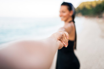 Follow me. Blur image of woman leading a man on a beach. Man's point of view.