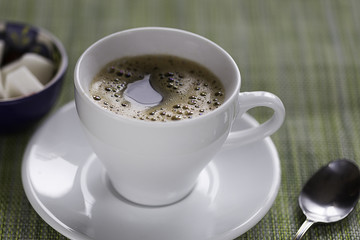 white coffee cup, tea spoon and sugar on a table