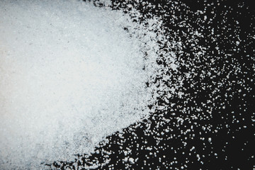 Spilled white sugar on a black background.