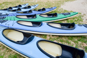 A lot of blue and green canoe kayaks with front parts of the noses for water sports, swimming lie...