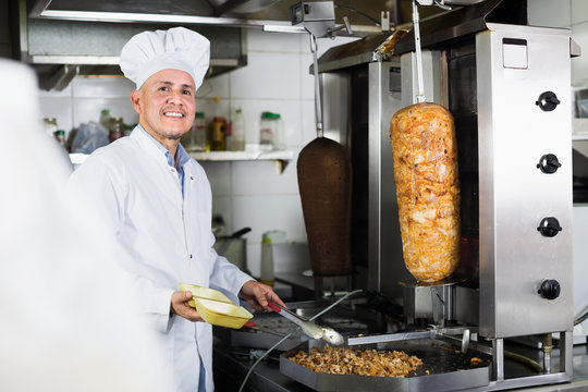 Mature man chef wearing uniform preparing kebab
