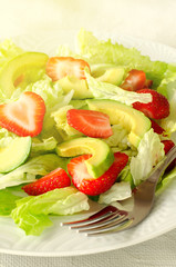 Salad with avocado, strawberries and lettuce on white background
