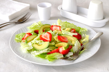 Salad with avocado, strawberries and lettuce on white background