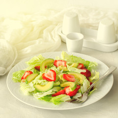 Salad with avocado, strawberries and lettuce on white background