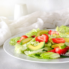 Salad with avocado, strawberries and lettuce on white background